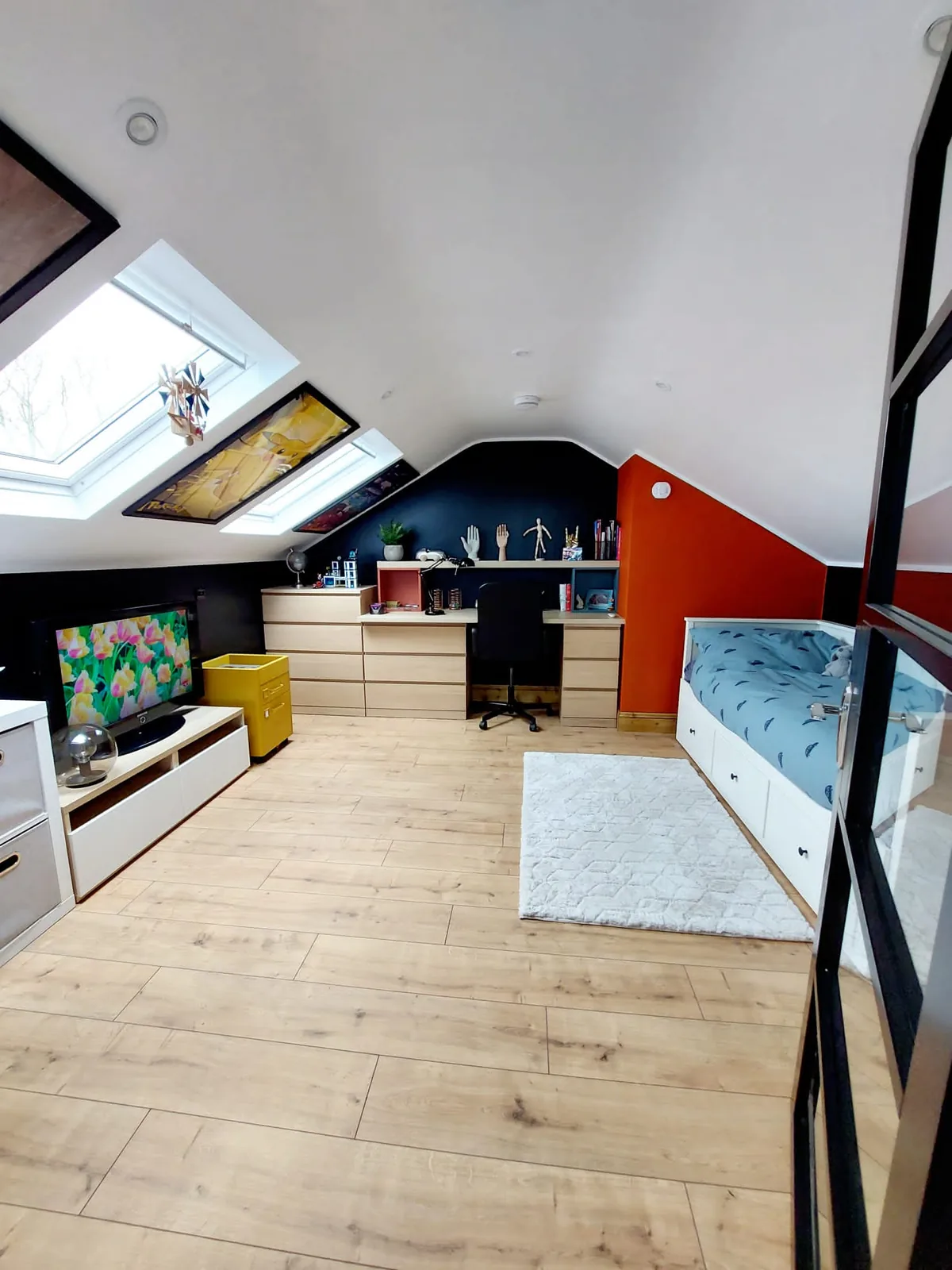 Teen attic with skylights, navy and orange feature walls and oak desk run